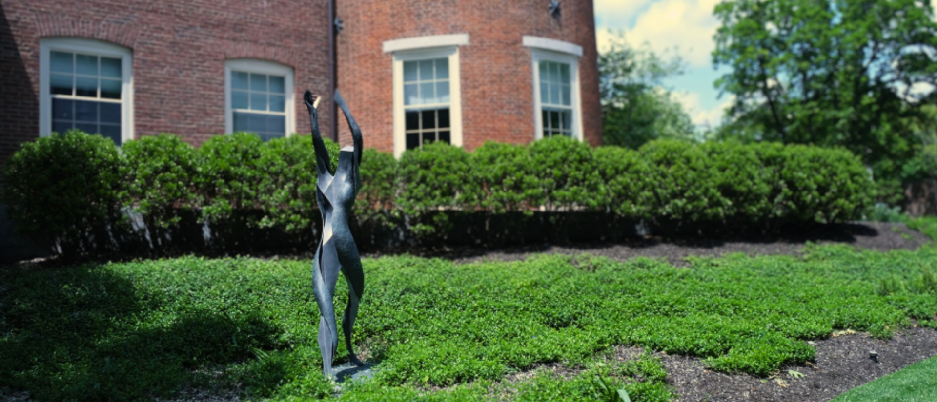 solitary statue on college campus reaching for the sky